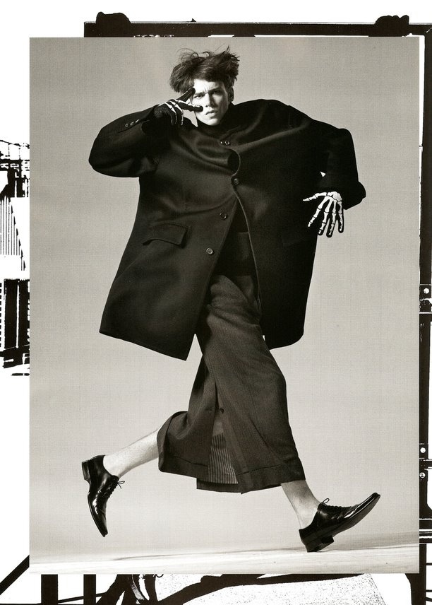 Black-and-white fashion editorial, figure mid-motion in an oversized coat